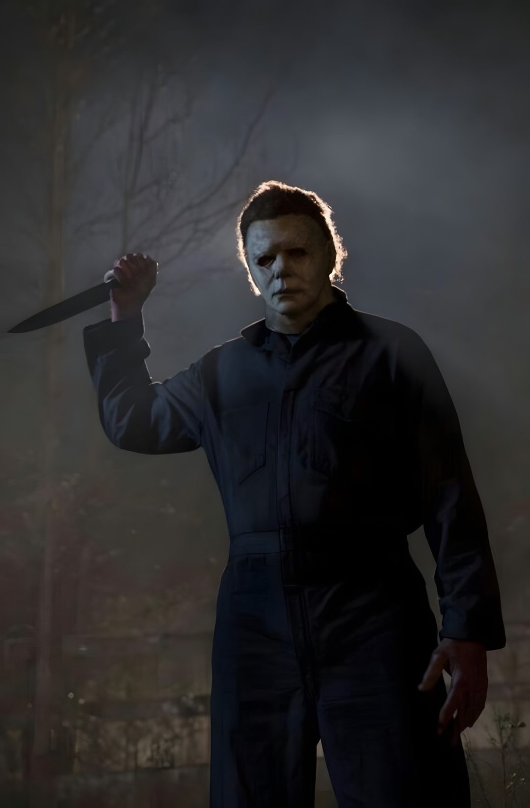 a man with a knife in his hand standing in front of a dark forest at night Halloween 2018 Michael Myers dark slate gray