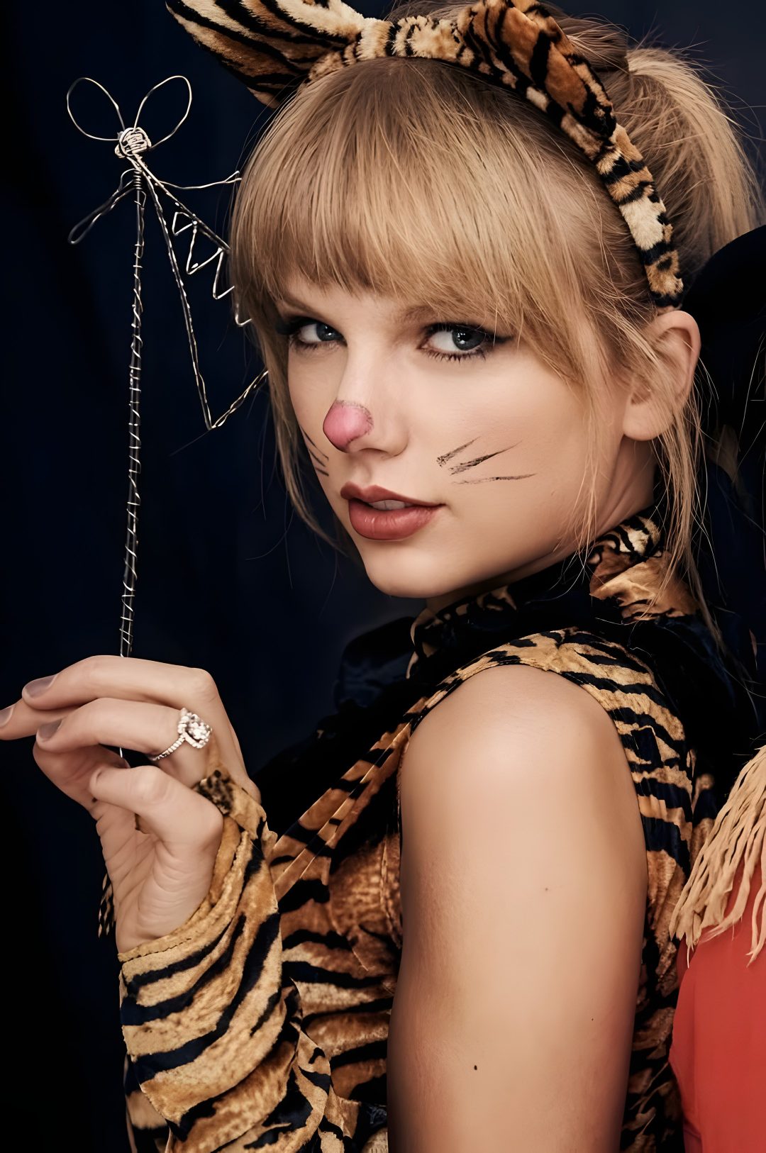 a woman with cat ears and makeup holding a string in her hand while wearing a tiger costume Taylor Swift Halloween saddle brown