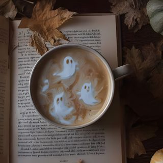 a cup of coffee with ghost faces in it on top of an open book surrounded by pumpkins Halloween Mood High Quality Aesthetic Photos, Cozy Fall Ipad, Fall Theme Aesthetic, dark slate gray