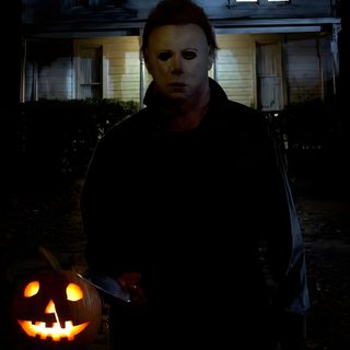 a man standing in front of a house with two pumpkins on the ground and one person holding a knife Halloween The Movie Horror Iphone, Michael Myers, Horror Villains, Halloween, black