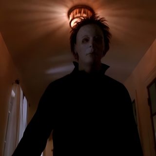 a person standing in a room with a light on above their head and an open door behind them Halloween H20 Michael Myers Scenes, Michael Myers Standing Still, Michael Myers House On Fire, black