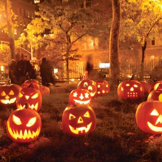 a group of pumpkins with faces carved into them in front of a house at night Halloween Pumpkin Patch Spooky Pumpkin Patch At Night, Lit Jack-o'-lanterns In A Garden, Halloween Pumpkin Patch, saddle brown