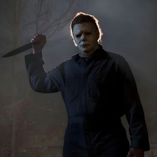a man with a knife in his hand standing in front of a dark forest at night Halloween 2018 Michael Myers dark slate gray