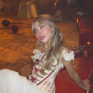a woman sitting on top of a red bench Halloween Sabrina Carpenter Sabrina Carpenter Circus, Sabrina Carpenter Circus Outfit, Sabrina Carpenter Halloween Inspo, saddle brown