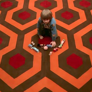 a woman sitting on the floor in front of a carpet with hexagons The Shining Laptop Halloween The Shining Carpet Room, The Shining Hotel Hallway Gif, The Shining Carpet Hd, saddle brown