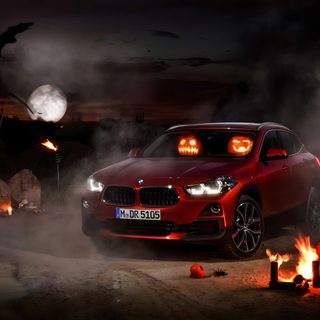 a red car parked in front of a campfire with pumpkins around it at night Bmw Halloween Car Halloween Decorations Exterior, Bmw Halloween Ad, Halloween Car Decoration Tips, black