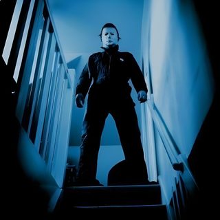 a man standing at the top of stairs in front of a stair case with blue light coming from behind him Halloween 1978 Michael Myers Halloween Aesthetic Michael Myers, Michael Myers In The Dark, Michael Myers 78, black