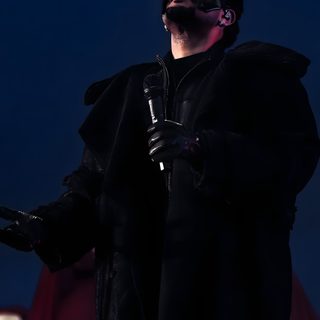 a man in a black outfit holding a microphone and wearing a mask on his face The Weeknd Halloween black