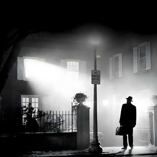 a man standing in front of a building on a foggy street at night with a lamp post Exorcist Halloween Exorcist Movie Halloween, Exorcist Black And White, The Exorcist Black And White,
