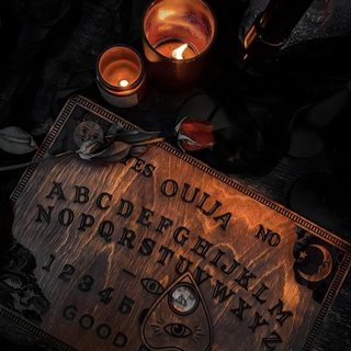two candles sitting on top of a table next to a sign that says ouula no 3 Halloween Ouija Board Ouija Aesthetic, Spirit Board Aesthetic, Black Ouija Board Aesthetic,