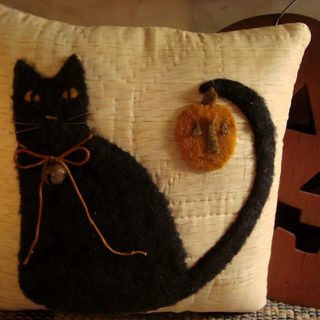 a black cat sitting on top of a pillow next to a pumpkin and a button Halloween Black Cat Pillow Cozy Fall Home Decor Inspiration, Black Cat Pillow With Pumpkin, Diy Halloween Pillow Ideas, maroon