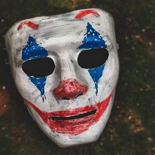 a white mask with blue and red painted on it's face sitting in the grass Cool Halloween For Boys Joker Mask 4k, Helloween Mask, Mask For Halloween, dark slate gray