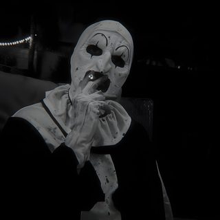 a person in a white mask and black jacket sitting down with their hand on his mouth Art The Clown Halloween Engel Tattoo Männer, Horror Photos, Scary Photos, Scary Movie Characters, black