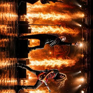 the backs performing on stage in front of an orange and yellow background with spotlights Mcr Halloween Mcr Concert, Music, maroon
