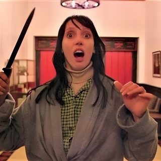 a woman holding two knives in her hands and looking surprised at the camera while standing in a hallway The Shining Laptop Halloween The Shining Wendy Knife, The Shining Stills, Horror Movie Stills Aesthetic, sienna
