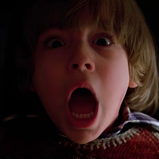 a young boy with his mouth open in the dark, making a shocked face and looking at the camera The Shining Laptop Halloween The Shining 1980 Danny, The Shining 1980 Movie Stills, Shining 1980, black