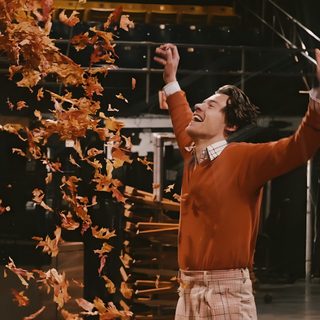 a man in red sweater throwing confetti on stage Harry Styles Halloween black