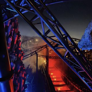 the stairs are lit up with red and blue lights in the dark night time sky Halloween Roller Coaster Halloween Roller Coaster, Dark Themed Amusement Park, Roller Coaster In The Dark, black