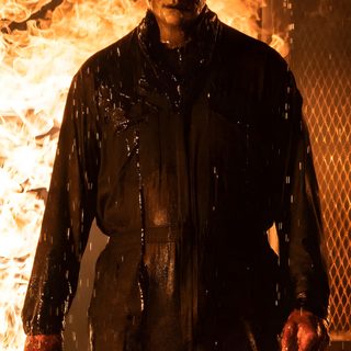 a man standing in front of a fire with his hands on his hips and holding a knife Halloween Kills Michael Myers Halloween Ends, Michael Myers Black Background, Halloween Kills Michael Myers, maroon