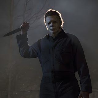 a man with a knife in his hand standing in front of a dark forest at night Halloween Film dark slate gray