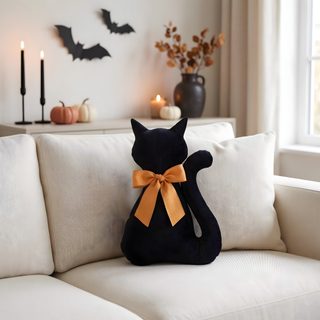 a black cat sitting on top of a white couch next to candles and pumpkins Halloween Black Cat Pillow silver