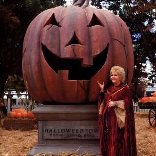 a woman standing next to a carved pumpkin Halloweentown Pumpkin Debbie Reynolds, Halloween Make, Halloween, Halloween Town Movie, saddle brown