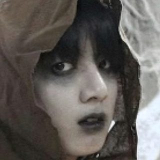 a woman with black hair and makeup wearing a brown hood over her head, looking at the camera Jungkook Halloween Historical Figures, dark olive green