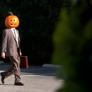 a man in a suit walking down the street with a pumpkin head on his head Dwight Halloween Dwight Pumpkin Head, The Office Halloween Episodes, The Office Spotify Covers, black