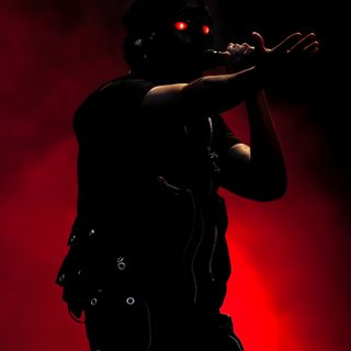 the silhouette of a man with red eyes on stage The Weeknd Halloween black