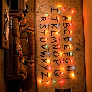 there is a room with lights on the wall and pictures hanging up against the wall Stranger Things Halloween Stranger Things Wall, Balloon Arch Decorations, Stranger Things Halloween, saddle brown