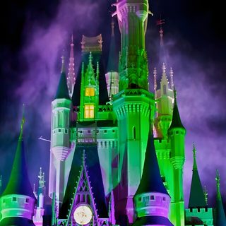 the castle is lit up with purple and green lights Magic Kingdom Halloween Wicked Castle, Walt Disney World Halloween Decorations, Purple And Green Haunted House, dark slate gray