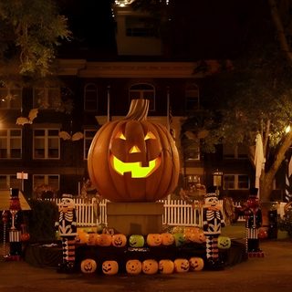 a large carved pumpkin sitting in the middle of a yard at night with decorations around it Halloweentown Pumpkin Halloween, Halloween City, Image Halloween, Black Halloween Dress,