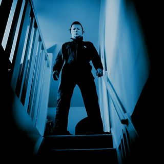 a man is standing on the stairs in front of an orange jack - o'- lantern John Carpenter Halloween Halloween Michael Myers Movies Rob Zombie, Michael Myers Horror, Mike Myers Halloween, black