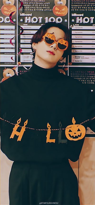 a woman wearing sunglasses and a black sweater with pumpkins on it, standing in front of a poster Jungkook Halloween Bts Halloween Costume, Jungkook Halloween, Bts Pumpkin Painting, dark slate gray