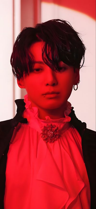 a woman with short black hair wearing a red shirt and earrings, standing in front of a white wall Jungkook Halloween Jungkook Photoshoot Me Myself, Jungkook Me Myself And I Photocards, Me Myself And Jungkook, crimson
