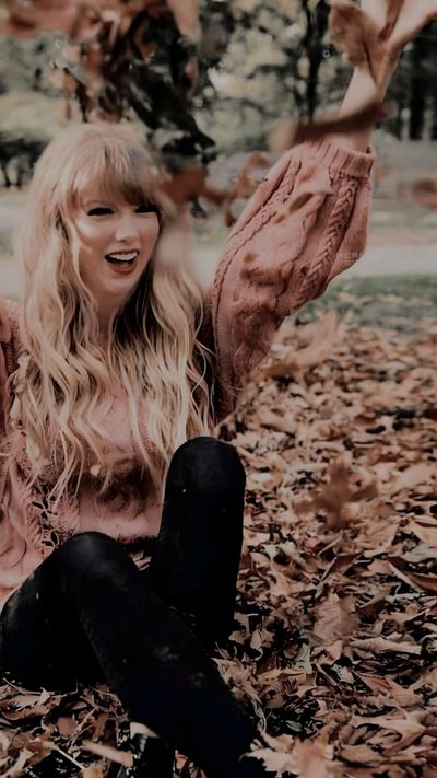 a woman sitting on the ground with her arms in the air and leaves all around her Halloween Taylor Swift Taylor Swift Fall Photoshoot, Taylor Swift Fall, Taylor Swift Happy Aesthetic, dark olive green