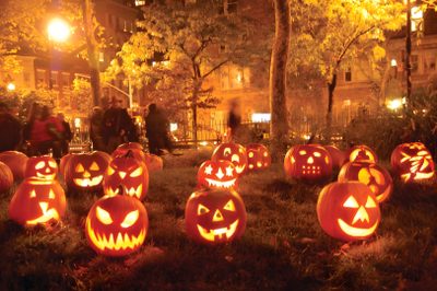 a group of pumpkins with faces carved into them in front of a house at night Halloween Pumpkin Patch Spooky Pumpkin Patch At Night, Lit Jack-o'-lanterns In A Garden, Halloween Pumpkin Patch, saddle brown
