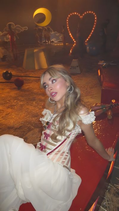 a woman sitting on top of a red bench Halloween Sabrina Carpenter Sabrina Carpenter Circus, Sabrina Carpenter Circus Outfit, Sabrina Carpenter Halloween Inspo, saddle brown