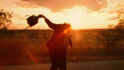 a person standing on the side of a road with their arms in the air while the sun is setting Texas Chainsaw Man Movie Halloween Orange Horror Movie, Slasher Movie Gif, Texas Chainsaw 3d 2013, saddle brown
