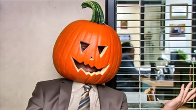 a man in a suit and tie with a pumpkin on his head, sitting at a table Dwight Halloween Dwight Pumpkin Head, Pumpkin Dwight, The Office Pumpkin, rosy brown