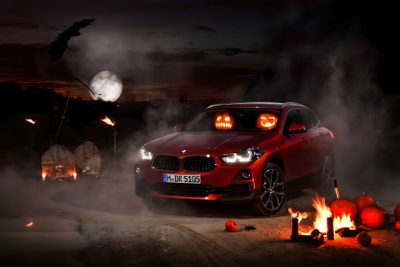 a red car parked in front of a campfire with pumpkins around it at night Bmw Halloween Car Halloween Decorations Exterior, Bmw Halloween Ad, Halloween Car Decoration Tips, black