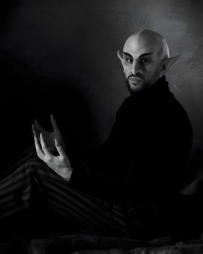 a bald man sitting on top of a bed wearing striped pants and holding his hands in the air Bad Bunny Halloween What We Do In The Shadows Nosferatu, Nosferatu Ears, Nosferatu Cosplay, black