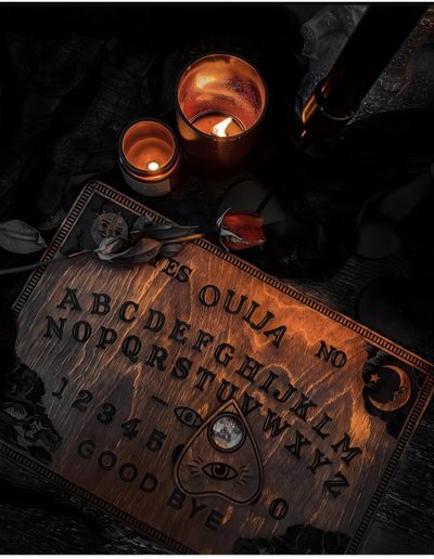 two candles sitting on top of a table next to a sign that says ouula no 3 Halloween Ouija Board Ouija Aesthetic, Spirit Board Aesthetic, Black Ouija Board Aesthetic,