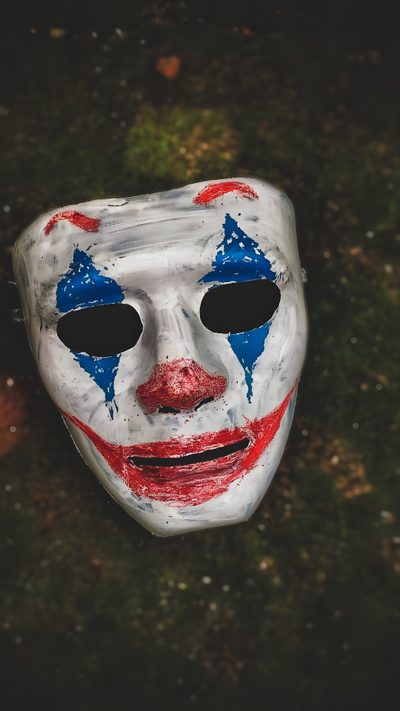 a white mask with blue and red painted on it's face sitting in the grass Cool Halloween For Boys Joker Mask 4k, Helloween Mask, Mask For Halloween, dark slate gray
