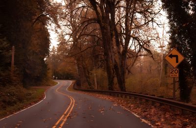 an empty road surrounded by trees and fallen leaves in the fall with a speed limit sign Halloween Road Fall Pc Aesthetic, Cozy Autumn Aesthetic Pc, Autumn Vibes Pc, saddle brown