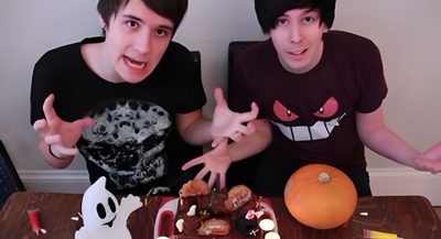 two young men sitting next to each other in front of a table with food on it Dan And Phil Halloween 2009 Dan And Phil Halloween Baking, Phil Lester Halloween, Dan And Phil 2012, dim gray