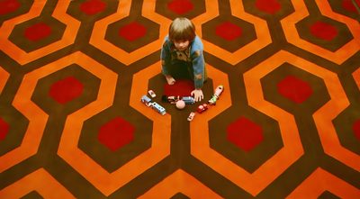 a person sitting on the floor in front of a carpet with hexagons The Shining Laptop Halloween The Shining Carpet Room, Shining Carpet, The Shining Carpet Hd, saddle brown