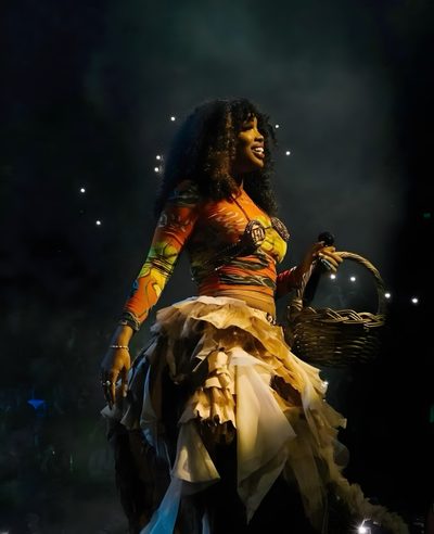 a woman in a costume on stage holding a basket with lights around her and smiling Sza Halloween Sza Aesthetic Photos, Artists Music, Sza Tour 2023, Sza Photography, Aesthetic Sza Photos, black