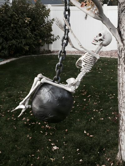 a skeleton sitting on top of a black ball in the grass next to a tree Wrecking Ball Halloween Skeleton Pics, Halloween Diy Outdoor, Halloween Outside, dark slate gray