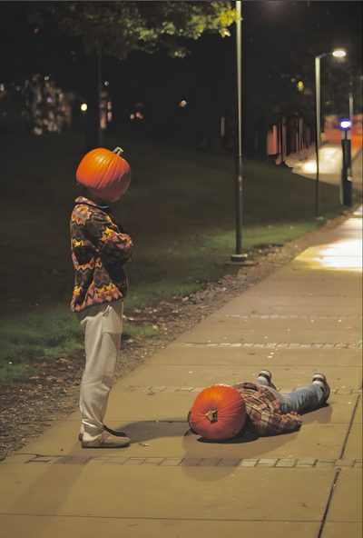 a young boy standing next to an orange pumpkin on the sidewalk with another person laying down Aesthetic Halloween Boys Halloween Kürbis Schnitzen, Halloween Photography, Have Inspiration, dark olive green
